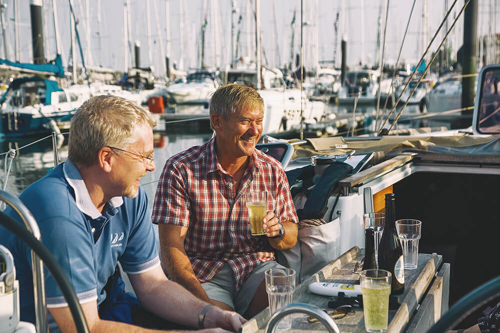 Two men sitting on a boat drinking champagne with boats in the backgroud at an MDL marina in Southampton