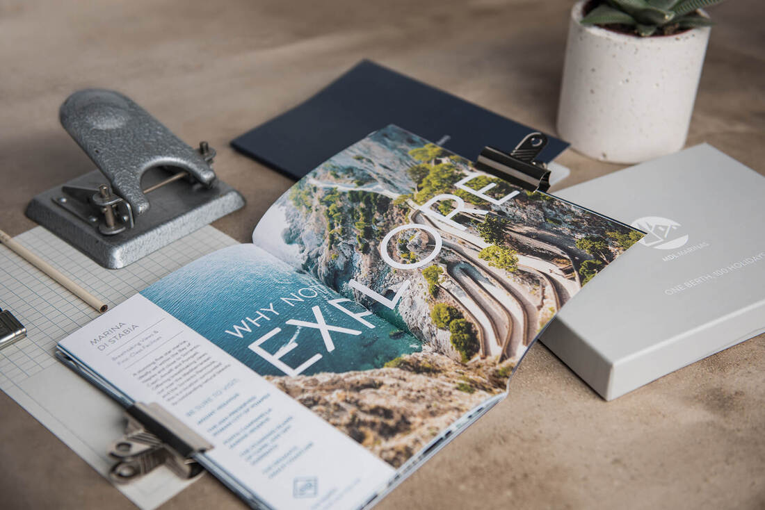 Styled photograph of MDL Marinas branded books and stationary